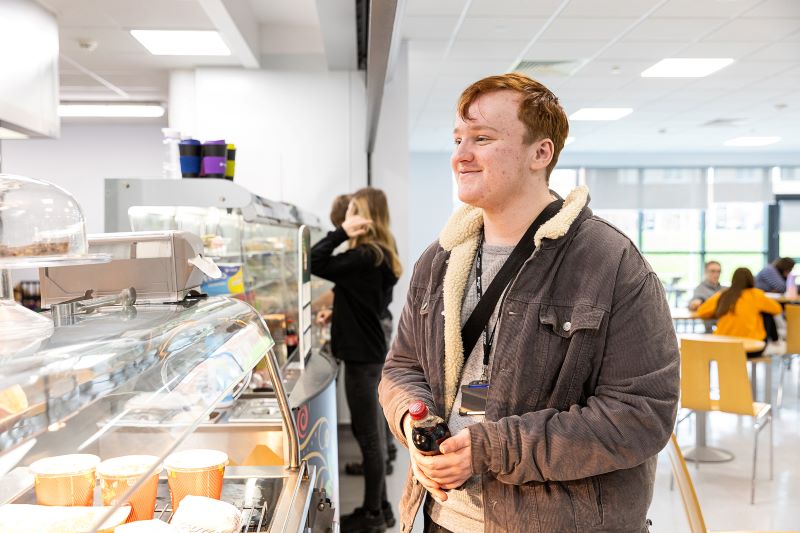 Image of male student at the canteen till point, looking at food options