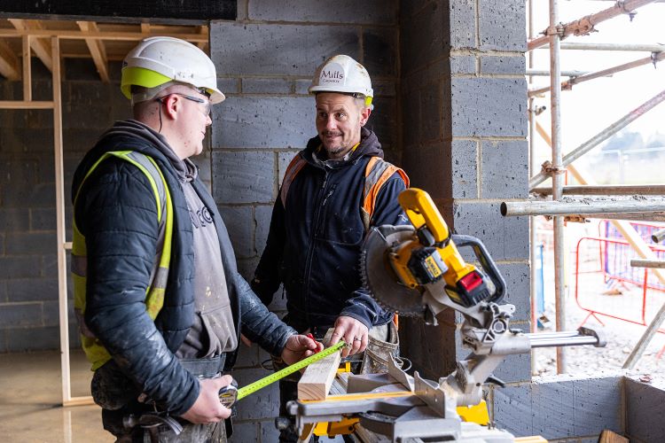 Image shows a Carpentry employer helping an apprentice on site.