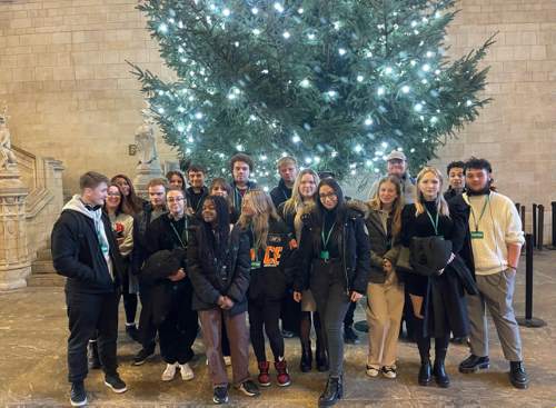 Students pose in London in front of a christmas tree.